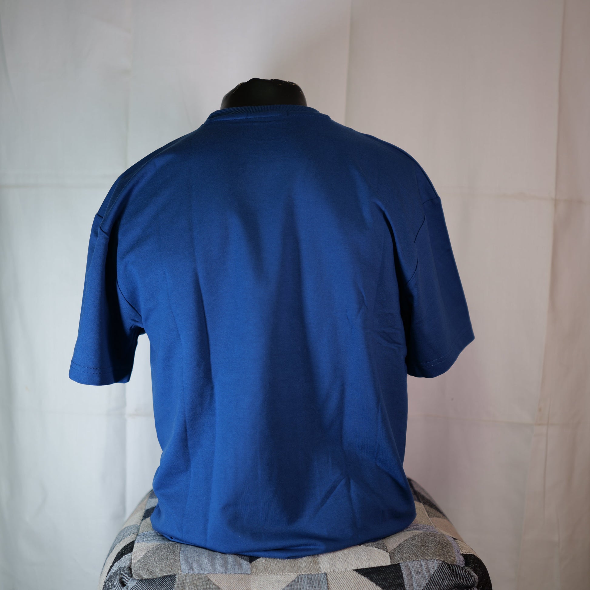 Blue shirt on a mannequin against a white curtain